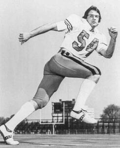 Vintage black-and-white photo of Kenny Cole running in his No. 54 football uniform.