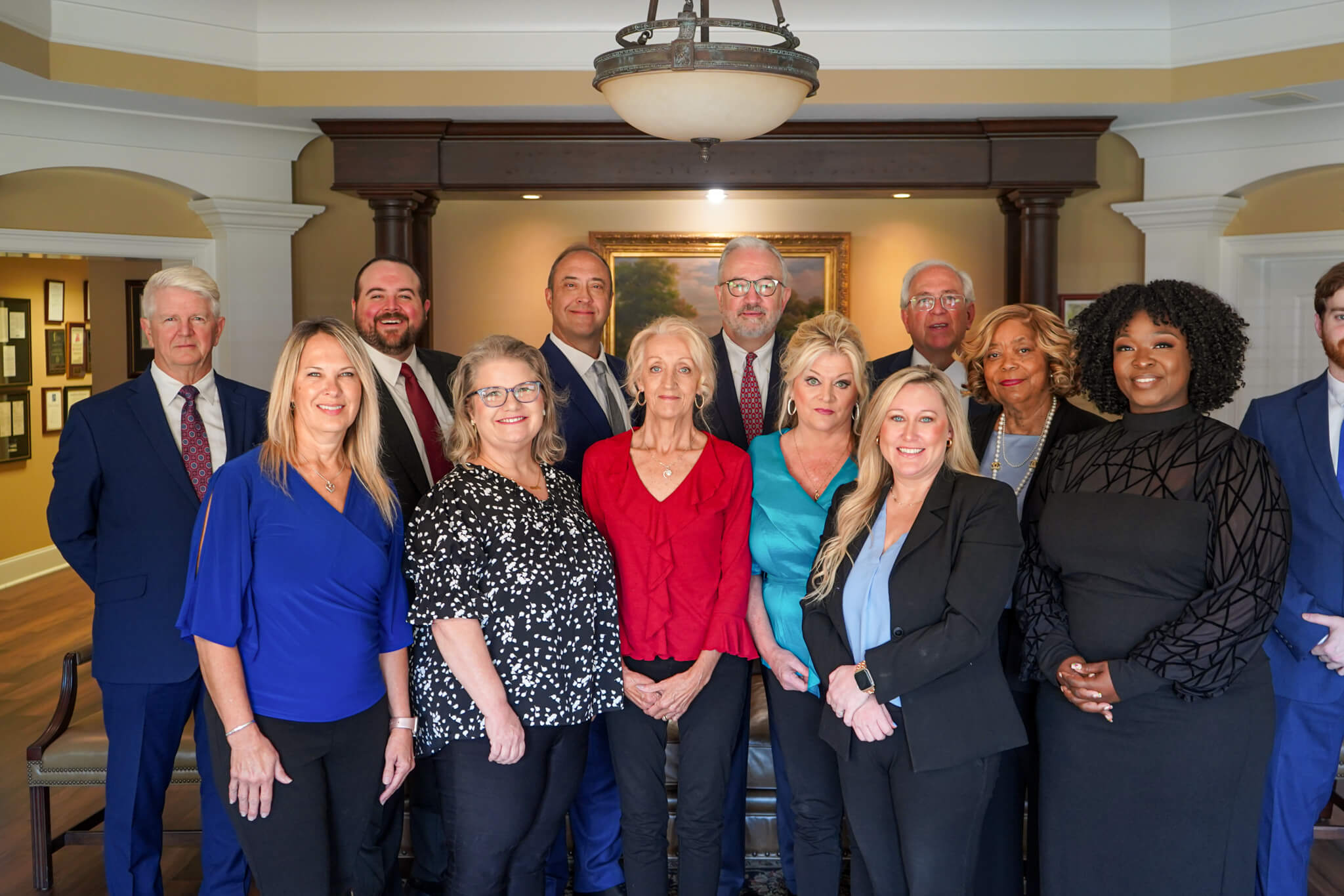 The attorneys and staff at the Personal Injury Law Firm of Conchin Cole Jordan & Sherrod pose for a group photo standing up in their office in Huntsville Alabama.